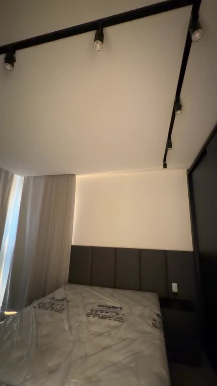 Quarto com cabeceira iluminada e trilho de spots
